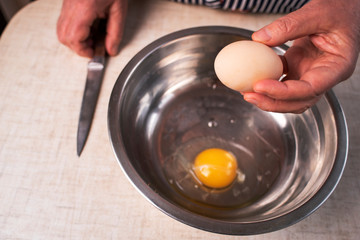 Close-up female hands in front of a transparent plate on a brown wooden table for cooking, on the sides a kitchen knife and eggs, homey cozy atmosphere in a rustic style