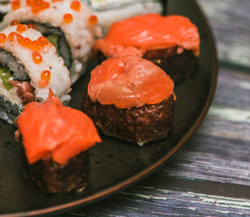 Various kinds of sushi served on dark plate macro
