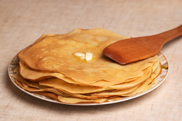 Pancakes on the white plate. Many pancakes are stacked. Thin pancakes with crispy crust. Maslenitsa. Pancakes for breakfast and carnival. Food background.
