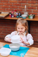 Little girl combining the ingredients for baking the cake. Kid taking part in baking workshop. Baking classes for children, aspiring little chefs. Learning to cook. Combining and stirring ingredients