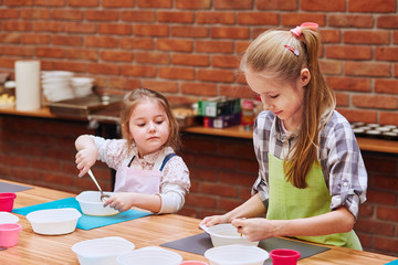 Little girls stirring the yolk with sugar. Kids taking part in baking workshop. Baking classes for...