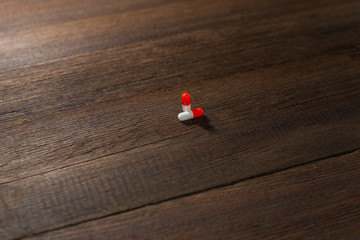 Red-white capsule pills close-up on a wooden background.