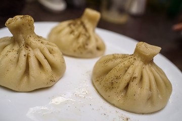 Tasty freshly prepared khinkali on a white plate close-up.