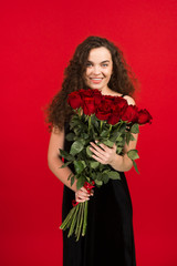 Front view of smiling girl in black dress with flowers isolated on red background