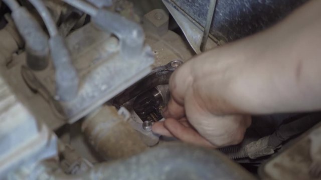 Auto mechanic repairs a part from the car chassis closeup