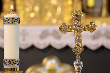 Holy cross with the crucified Christ and candle in the church with empty space for text