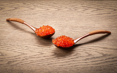 Red caviar in wooden spoons, against a background of dark oak
