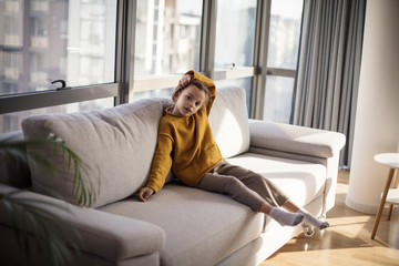 Little girl sitting on sofa at home.