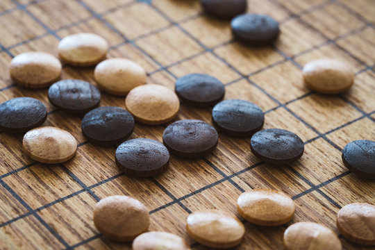 Wooden Mixed Chips Over A Board Of The Traditional Chinese Game Called GO