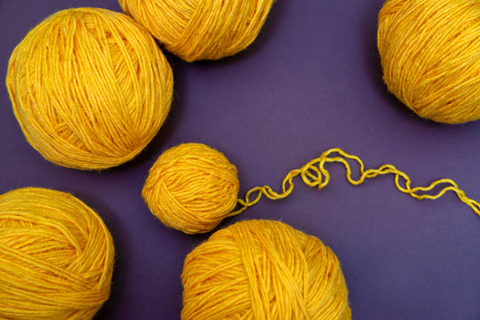 Yellow Balls of yarn for knitting on the pirple background