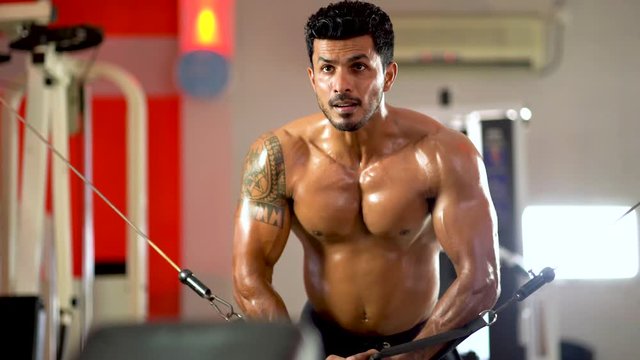Muscular bodybuilder at cable crossovers fitness men pumping up muscles. Workout fitness exercises and bodybuilding concept background
