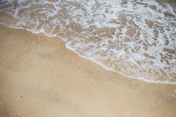 Fototapeta na wymiar Beautiful natural photo background with empty copyspace. White foamy sea wave splashing at sandy beach peacefully.