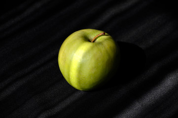 Big green apple on striped dark gray and light gray background
