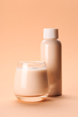 Coconut or almond milk with collagen on pastel coral background in bottle and glass