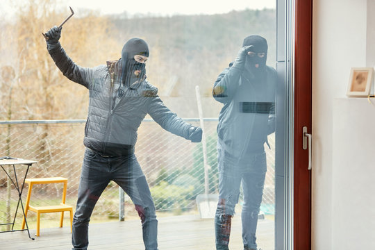 Einbrecher schlagen Scheibe einer Tür ein vom Haus