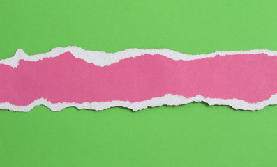 pieces of torn pink paper texture on green paper background, copy space.