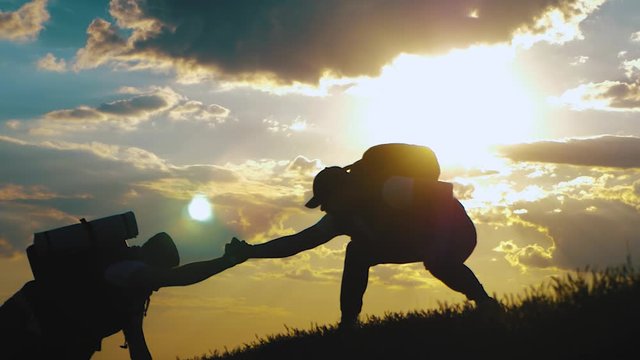 Silhouette of the team on the peak of mountain. Sport and active life of people. Teamwork assistance, help each other on top of mountain.