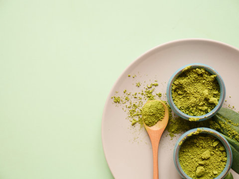 matcha tea on grey plate with spoon and leaf on grean background. Concept healthy drink, copyspace, flatlay, top view