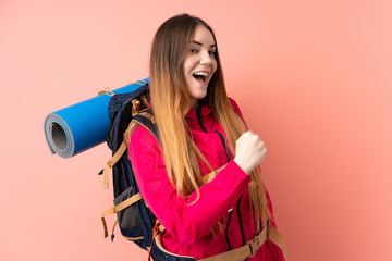 Obraz premium Young mountaineer girl with a big backpack isolated on pink background celebrating a victory