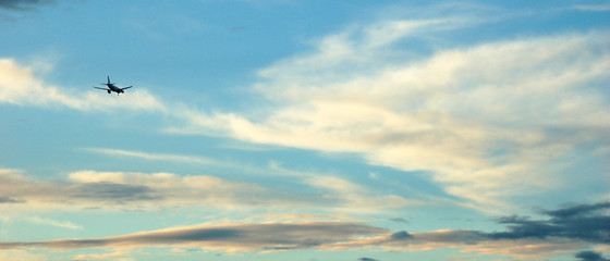 Bannière d'une petite silhouette d'avion dans un beau ciel ensoleillé et quelques nuages