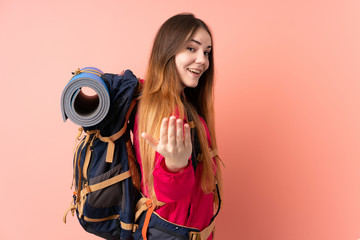 Obraz premium Young mountaineer girl with a big backpack isolated on pink background inviting to come