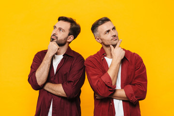 Image of two handsome men thinking and looking upwards at copyspace