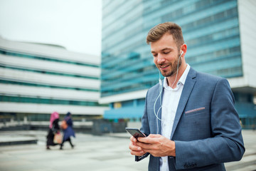 Fototapeta premium Businessman standing and using smartphone at business center