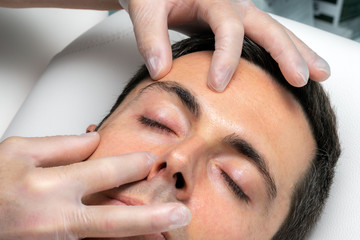 Hands with medical exam gloves inspecting eyelid of middle aged man.