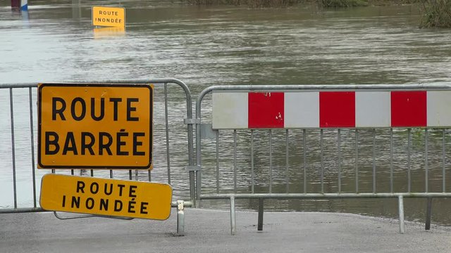 Water over road, Road flooded by overflow of a river and danger road sign