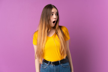 Young caucasian woman isolated on purple background doing surprise gesture while looking to the side