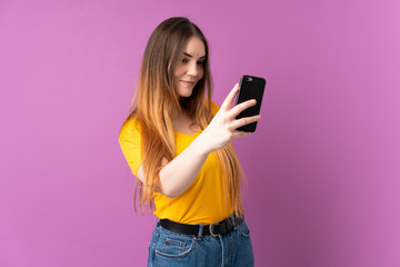 Young caucasian woman isolated on purple background making a selfie