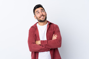 Young handsome man with beard wearing a corduroy jacket over isolated white background looking up...