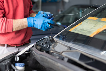 Car repair service, man working on glass replacement. Windshield insurance, safety and driving concept. Automotive industry.