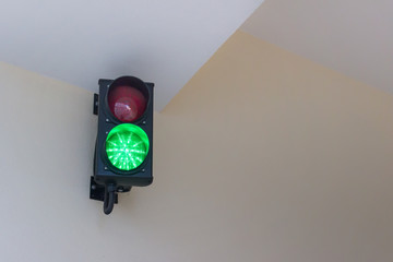 Traffic light hanging on the wall and showing green light ON.