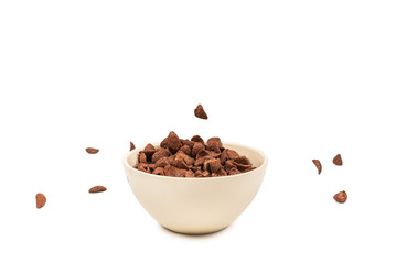 Chocolate corn flakes falling to the white bowl isolated on white. Motion.