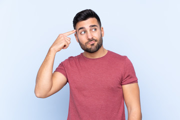 Young handsome man with beard over isolated blue background making the gesture of madness putting finger on the head