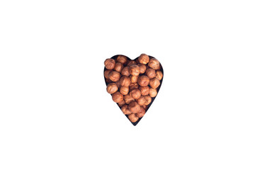Healthy eating, dieting, vegetarian food concept. Close up of peeled hazelnut in heart shape form on white background