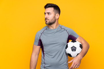 Man over isolated yellow background with soccer ball