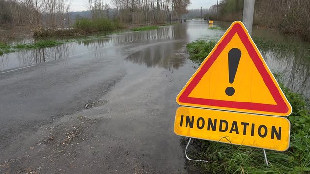 Timelapse Water over road, Road flooded by overflow of a river and danger road sign