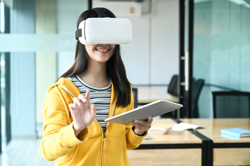 Cropped shot of a young female student wearing a VR glasses and using a laptop.