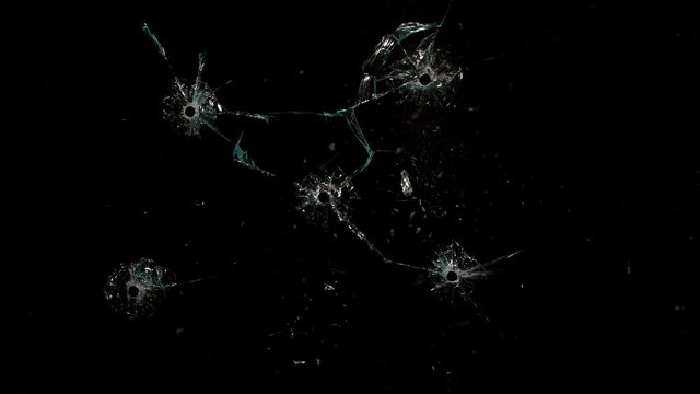 Shot Glass breaking with bullet holes on black background