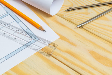 Rolled house diagrams and accessories for drawing lying on construction drawing and wooden boards