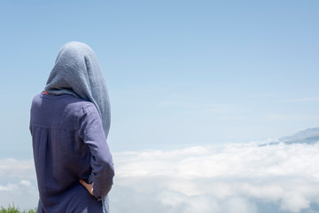 young man standing on the mountain above clouds