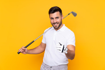 Man over isolated yellow background playing golf and pointing to the front