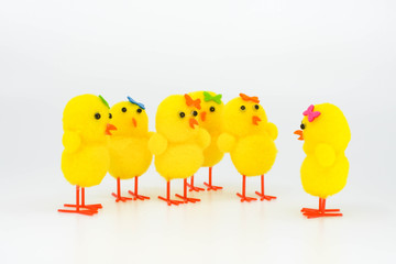 Cute yellow model chicks in a group. One chick is talking to the rest of the group against a plain white background