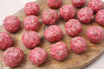 Raw meatballs of beef on a wooden board