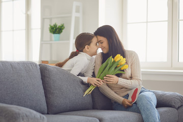 Happy mothers day. Daughter congratulates hugs his mother holds a bouquet of flowers in the room.