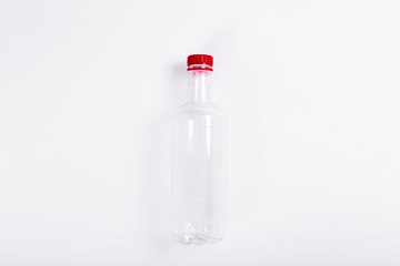 Empty transparent plastic bottle with a red cap on a white background