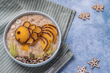 Kids breakfast oatmeal porridge with fruit look like a golden fish