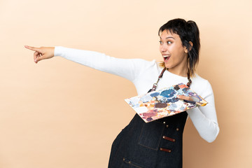 Young artist man holding a palette over isolated background pointing finger to the side